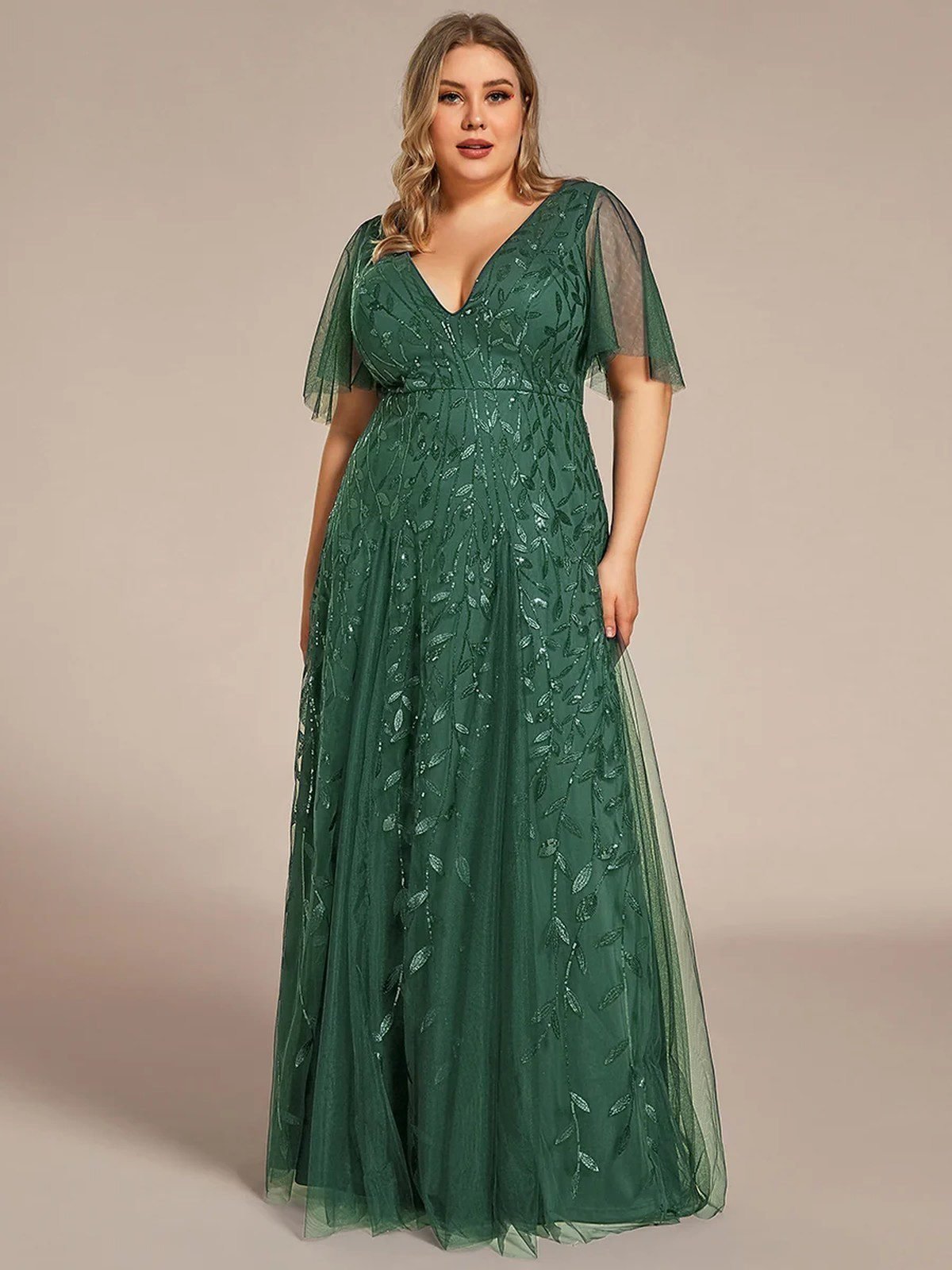 Plus size woman in an emerald green fit and flare dress for a wedding