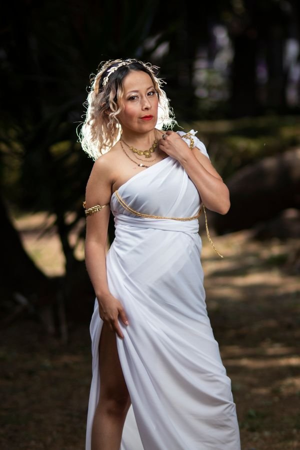 Woman wearing a Greek goddess Halloween costume with white draped dress