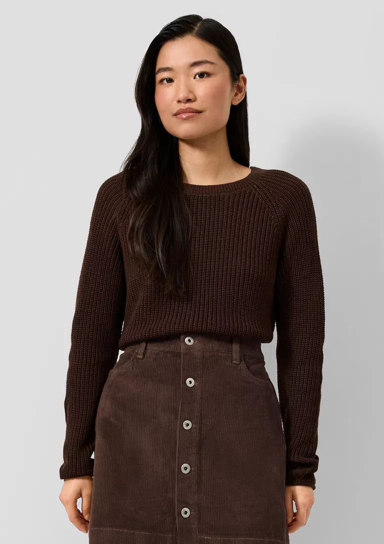 Woman wearing a corduroy midi skirt with a chunky knit sweater