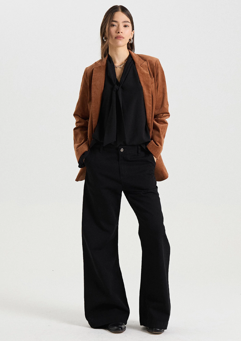 Woman wearing a rust corduroy blazer with black wide-leg trousers