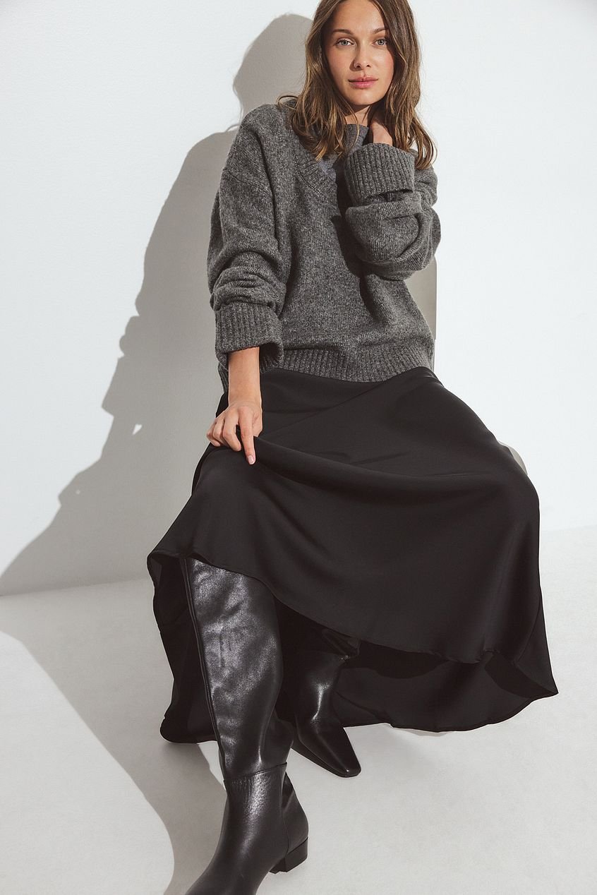 Woman in satin midi skirt with black leather knee high boots