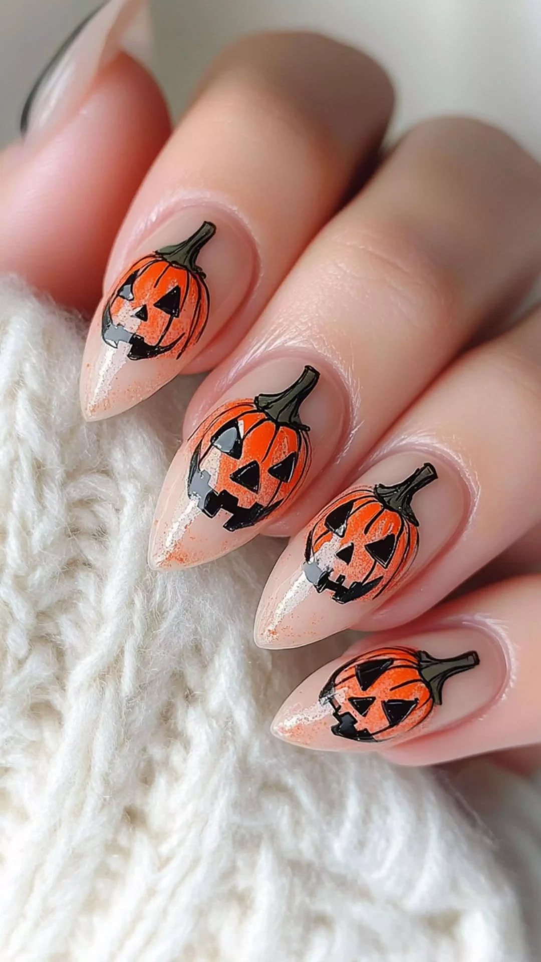 Nude pink Halloween nails with a jack-o'-lantern face accent nail