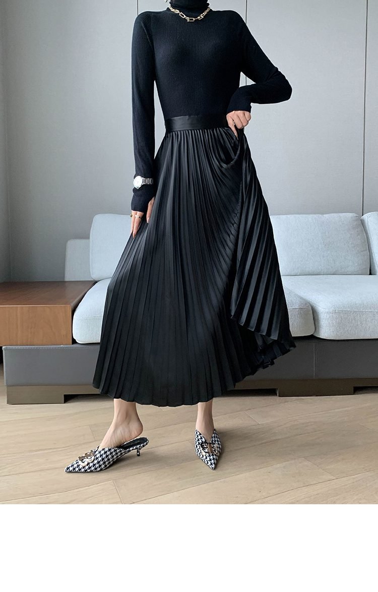 Woman in fitted turtleneck tucked into pleated midi skirt with loafers