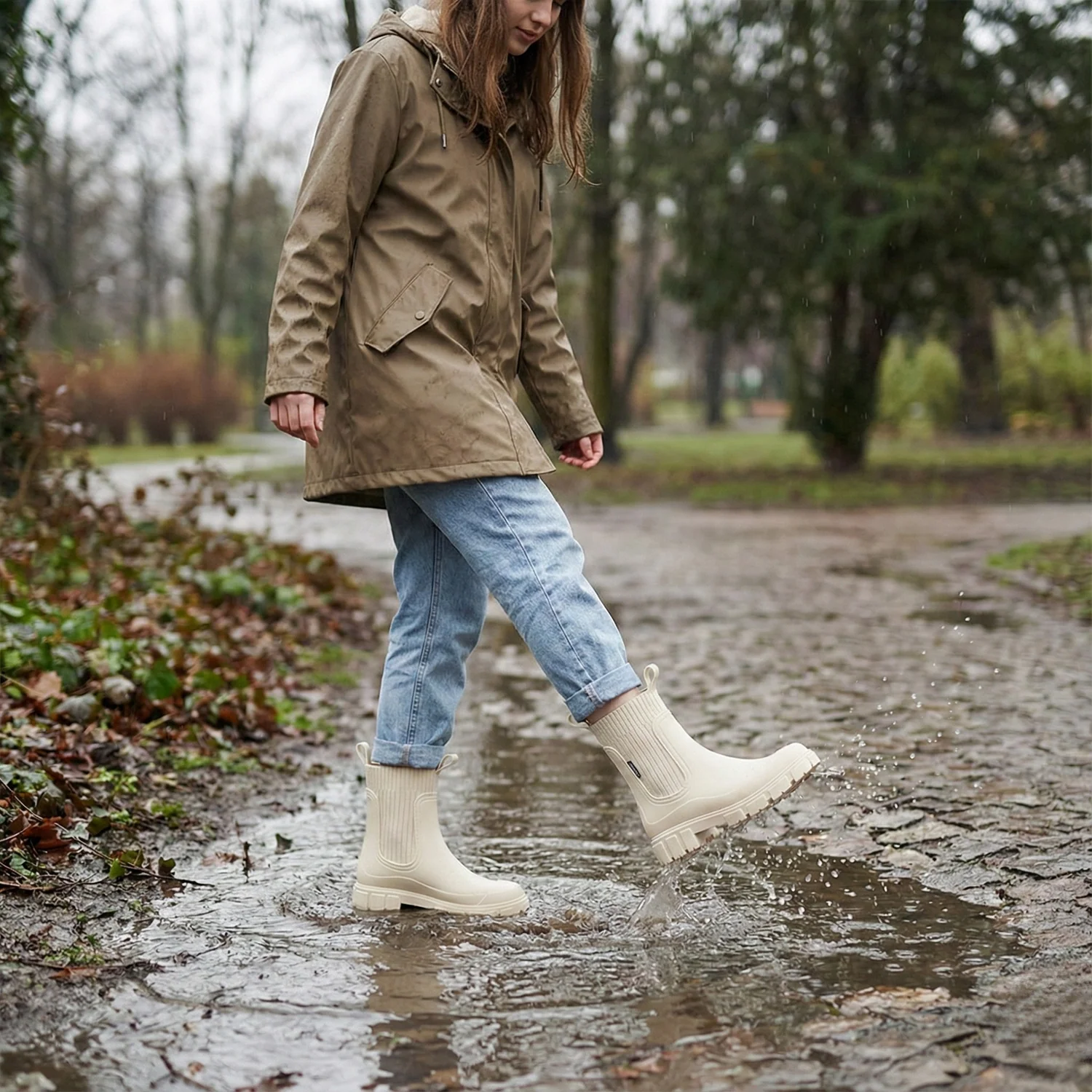 Woman in hooded raincoat with jeans and waterproof Chelsea boots on rainy day