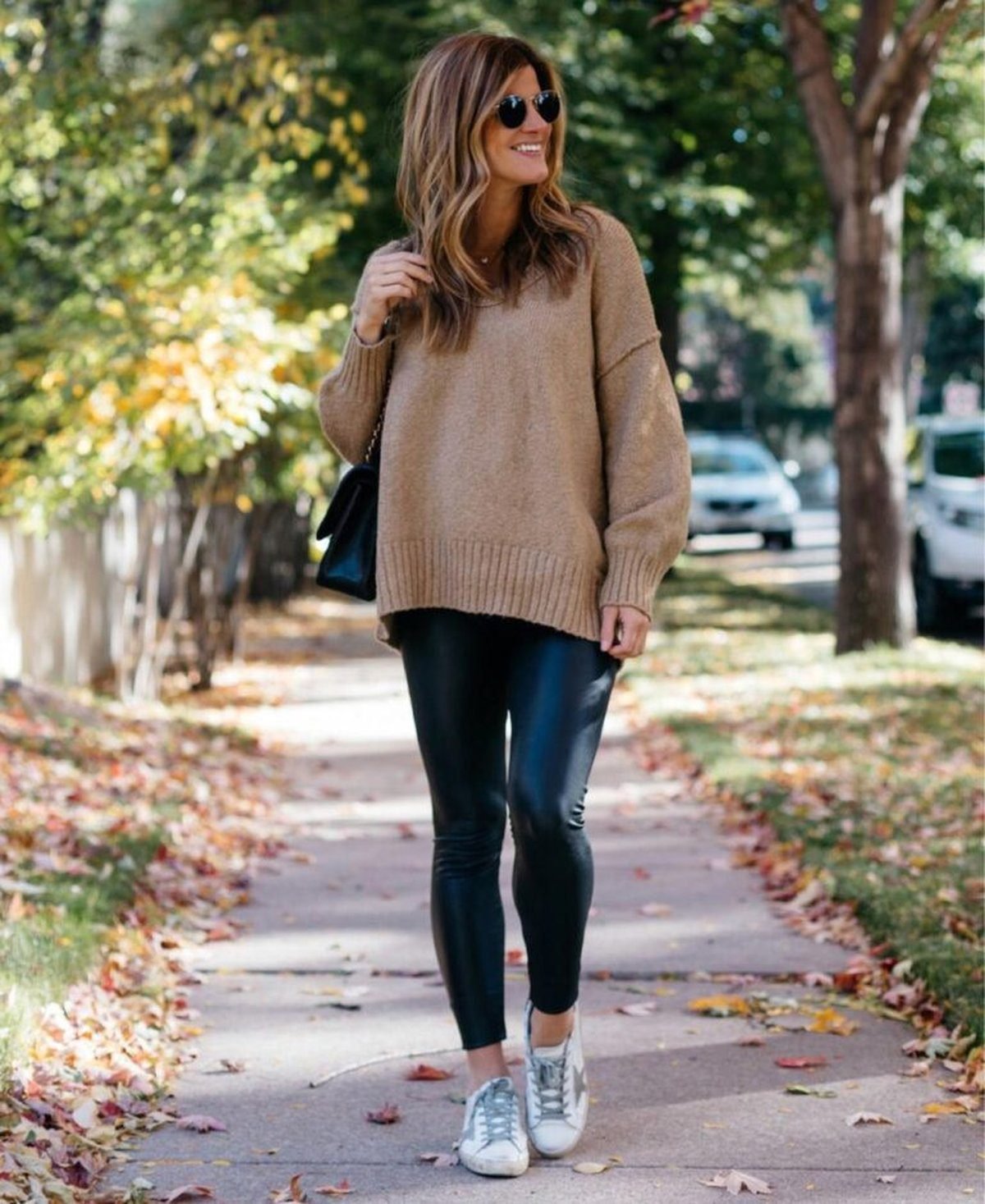 Woman wearing an oatmeal sweatshirt with black leather leggings and ankle boots