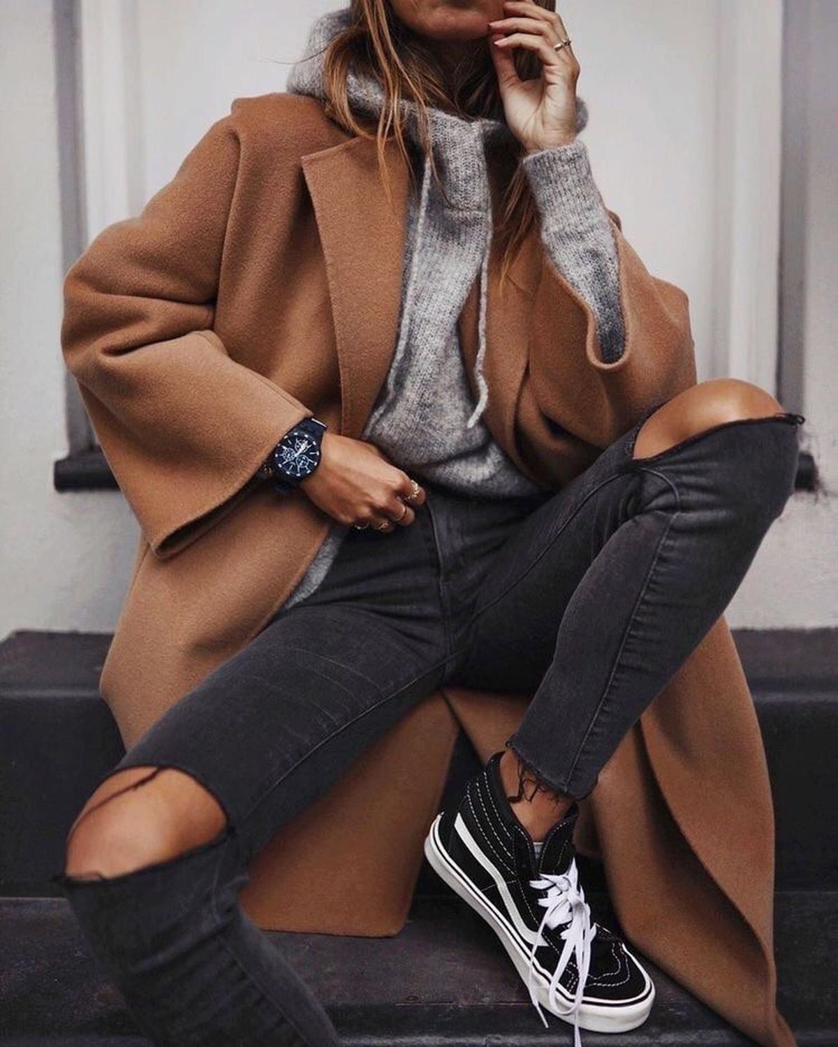 Woman styling a sweatshirt with an oversized wool coat and chunky white sneakers