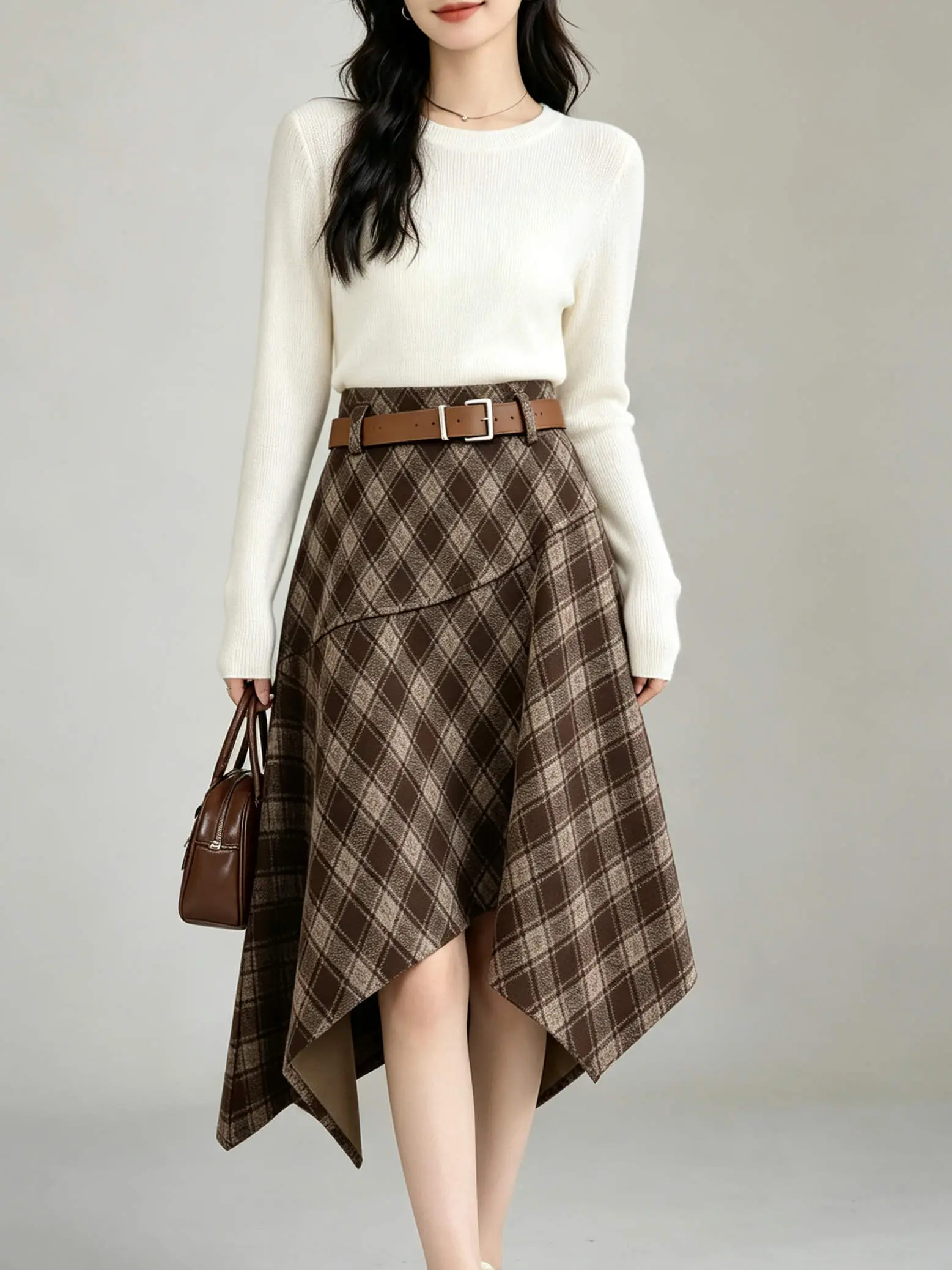 Woman wearing a plaid midi skirt with a tucked-in cream sweater