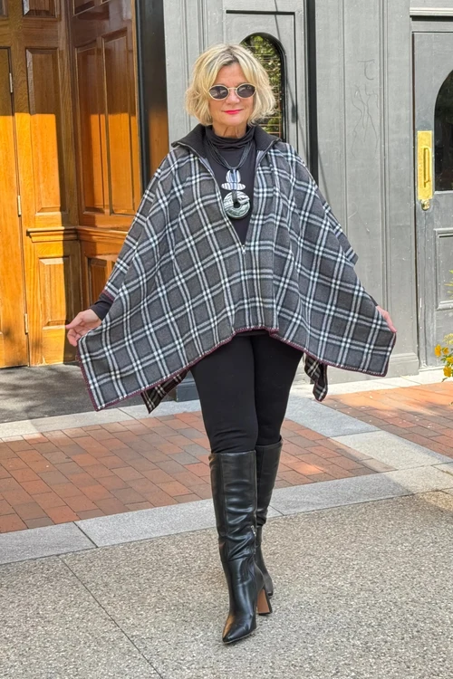 Woman wearing a plaid cape over a sweater and jeans