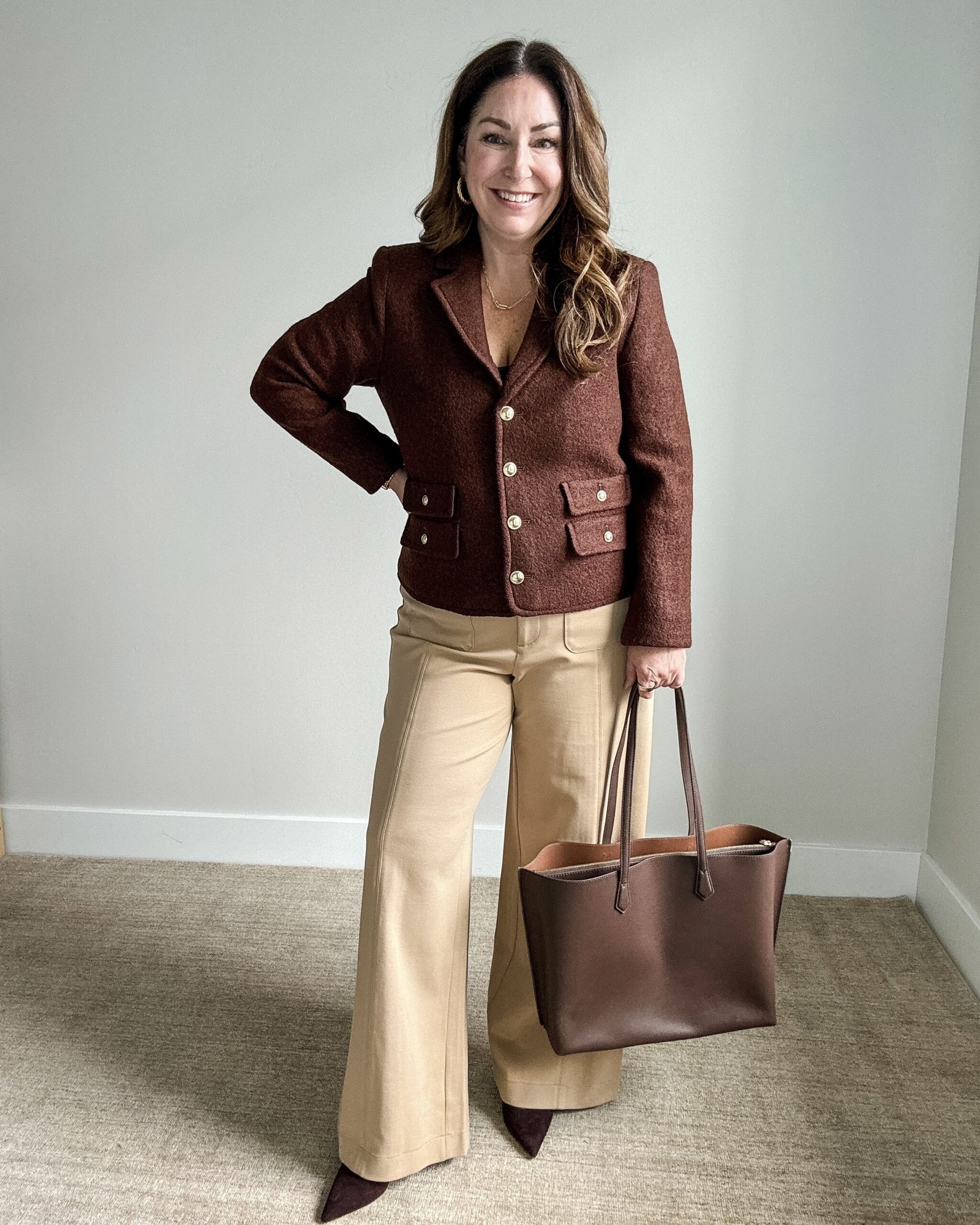 Woman in a burgundy cashmere sweater tucked into a pleated midi skirt for work