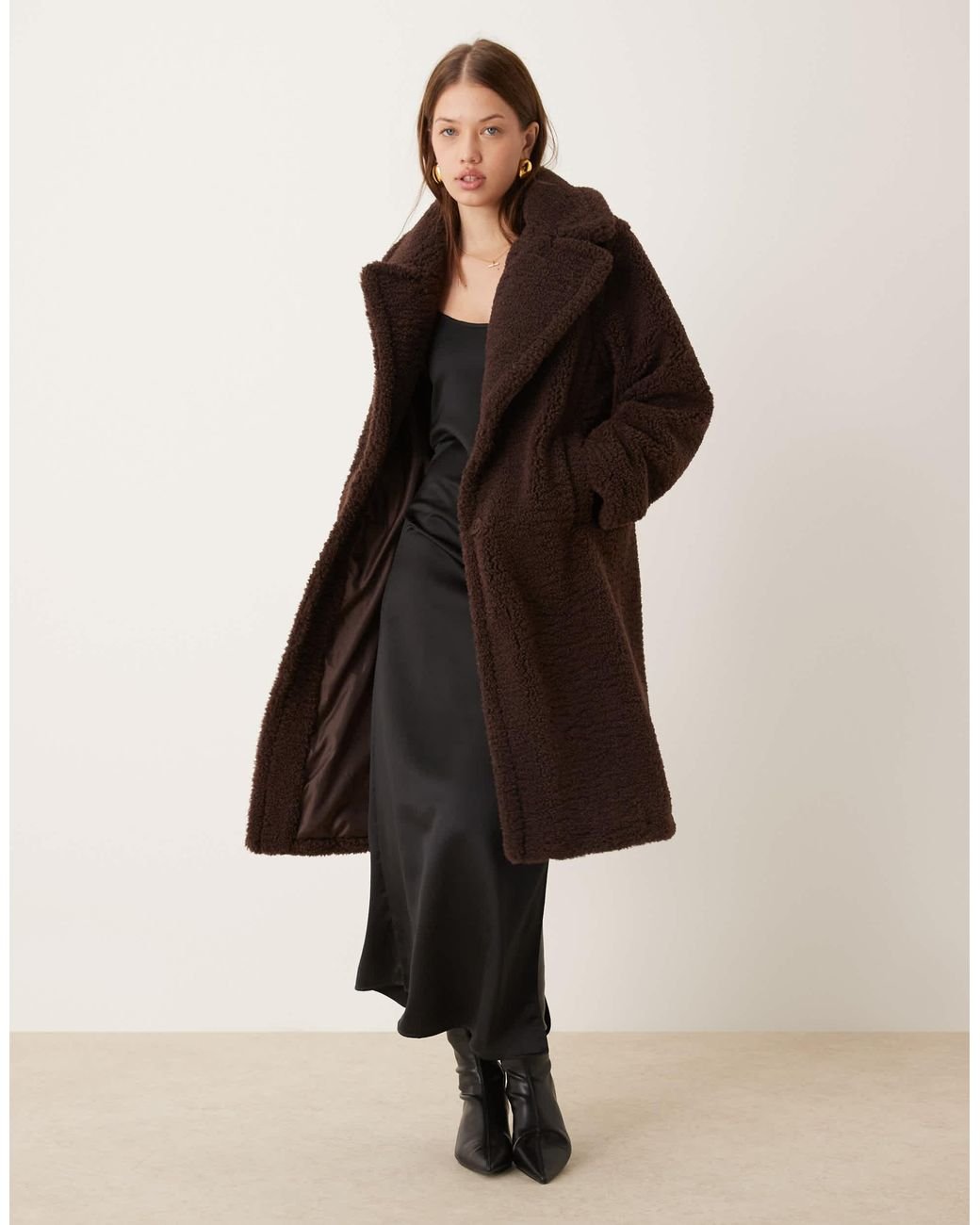 Woman wearing brown faux fur coat over satin slip dress