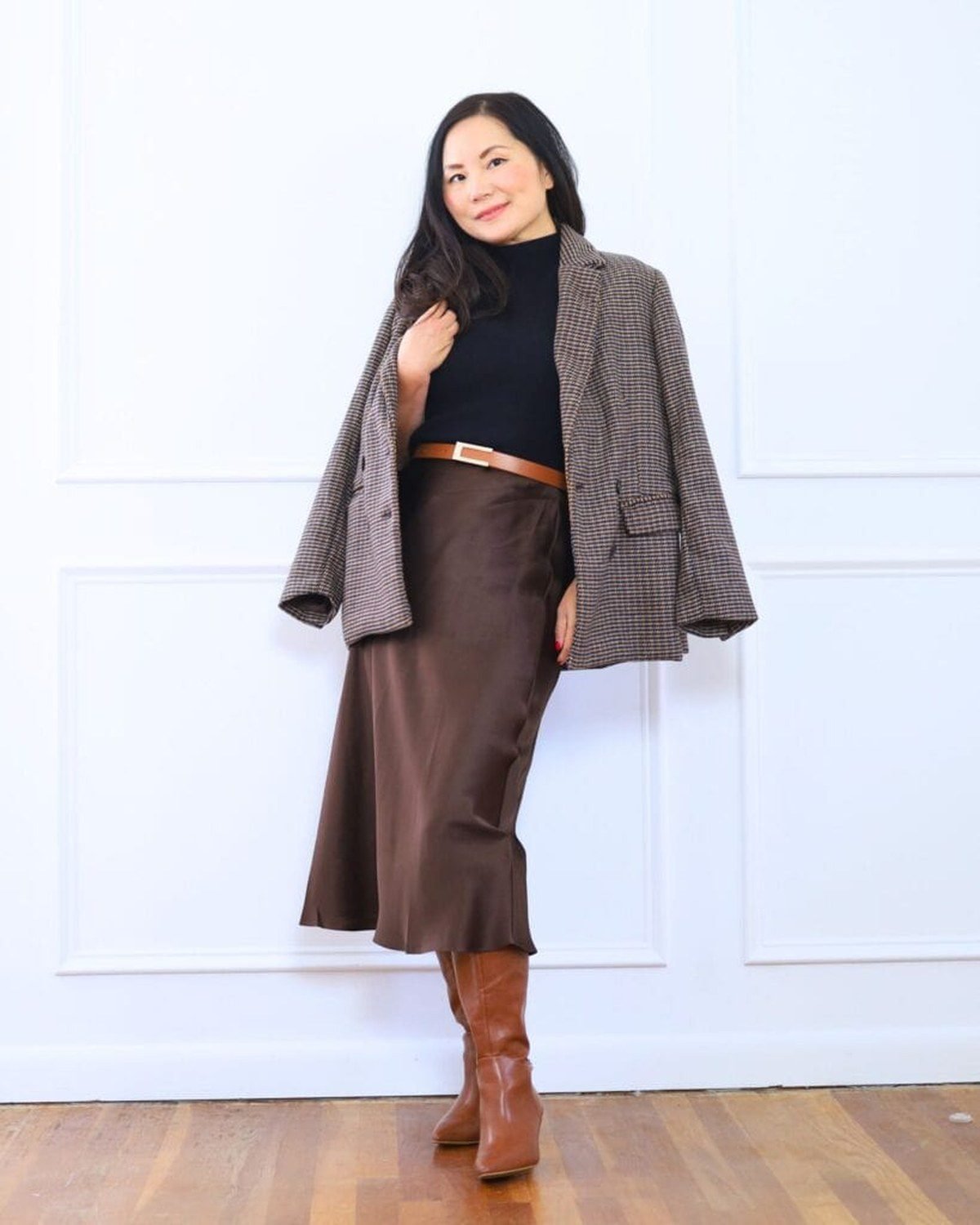 Woman wearing a plaid blazer with dark jeans and heeled ankle boots in fall