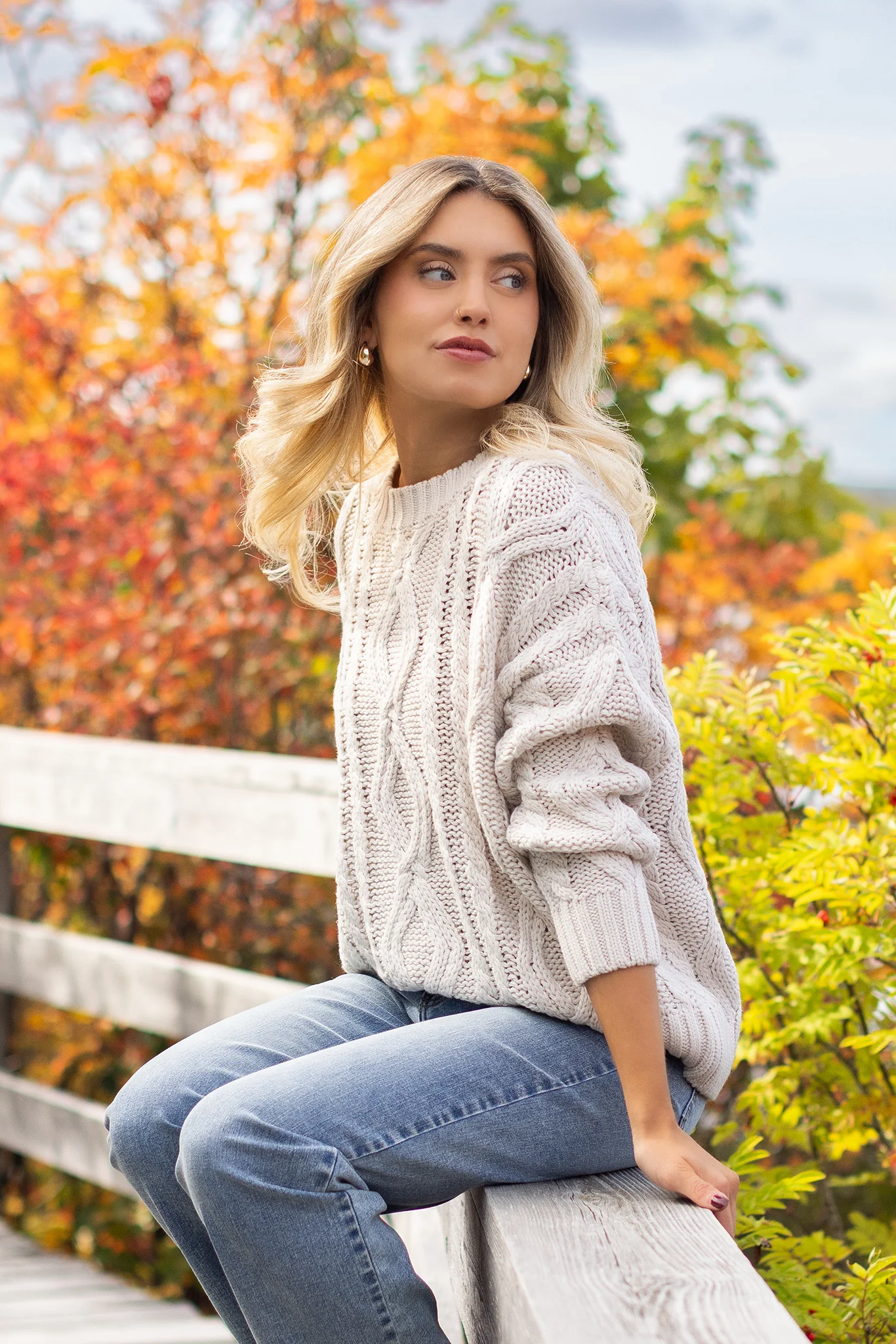 Woman in cream chunky-knit sweater with jeans