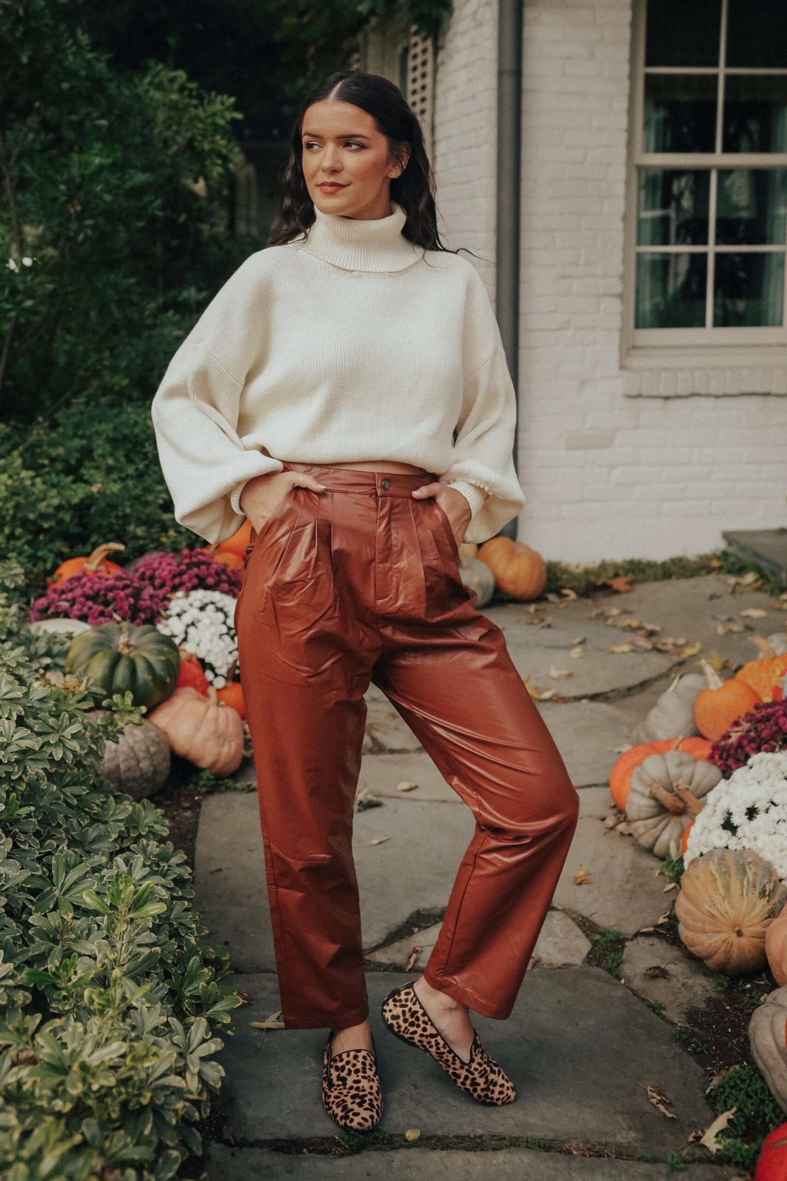 Woman in brown leather pants with a cream chunky sweater and boots