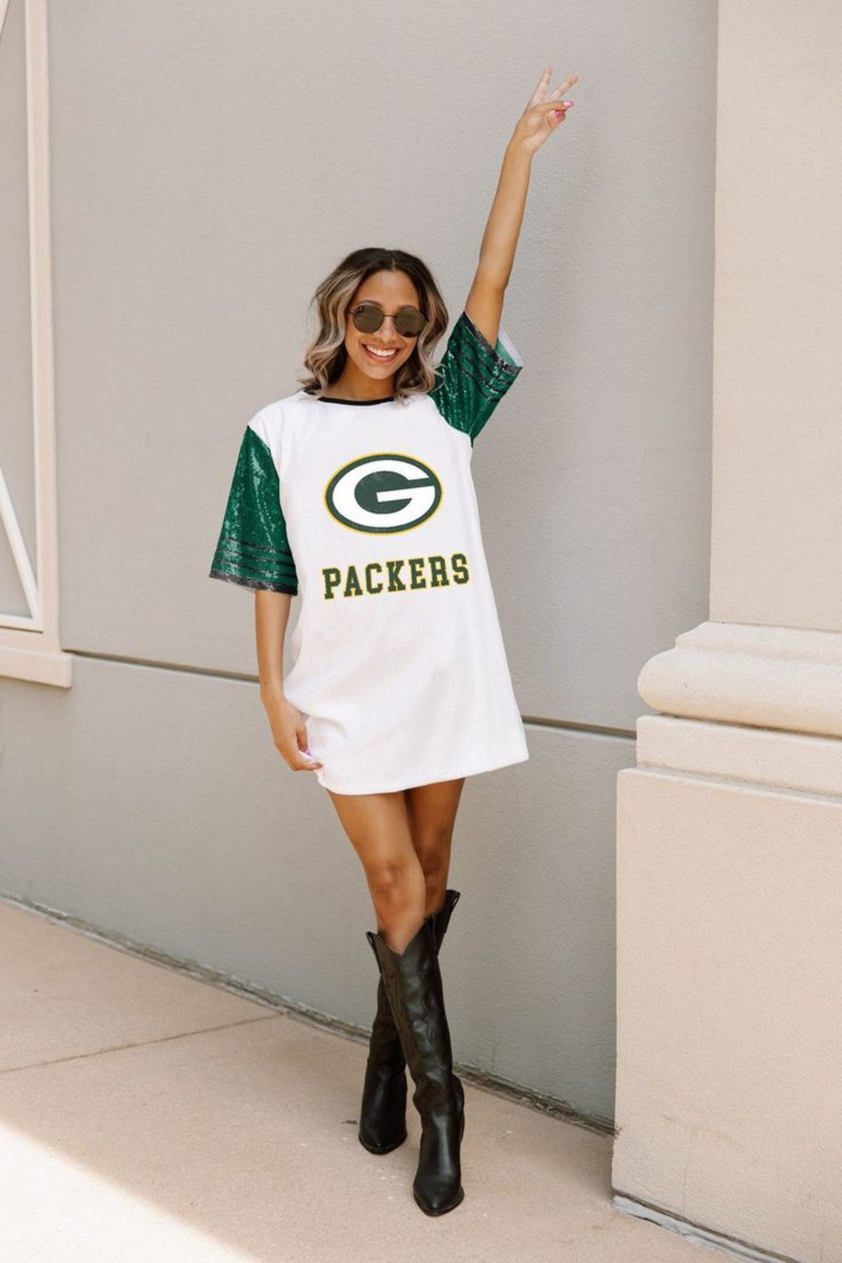 Woman styling an oversized football jersey as a dress with knee-high boots