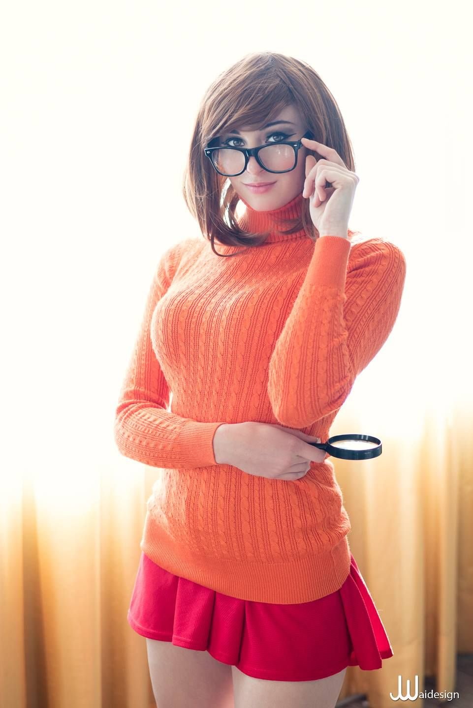 Woman dressed as Velma with jeans orange sweater and glasses