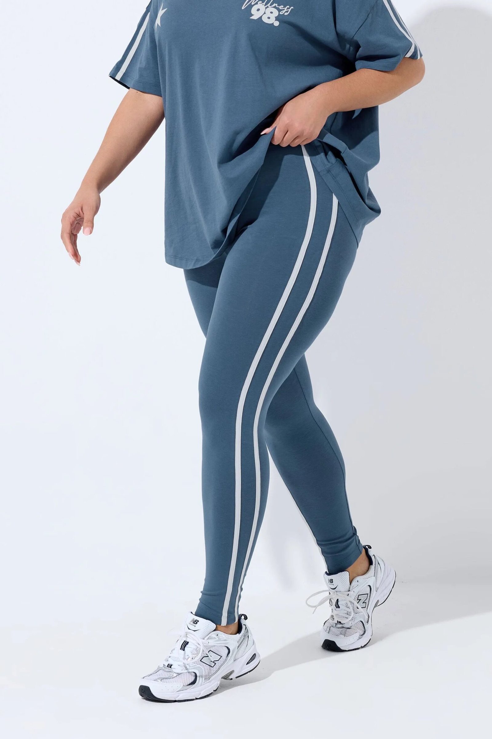 Woman wearing an oversized jersey as a cover-up over leggings with sneakers
