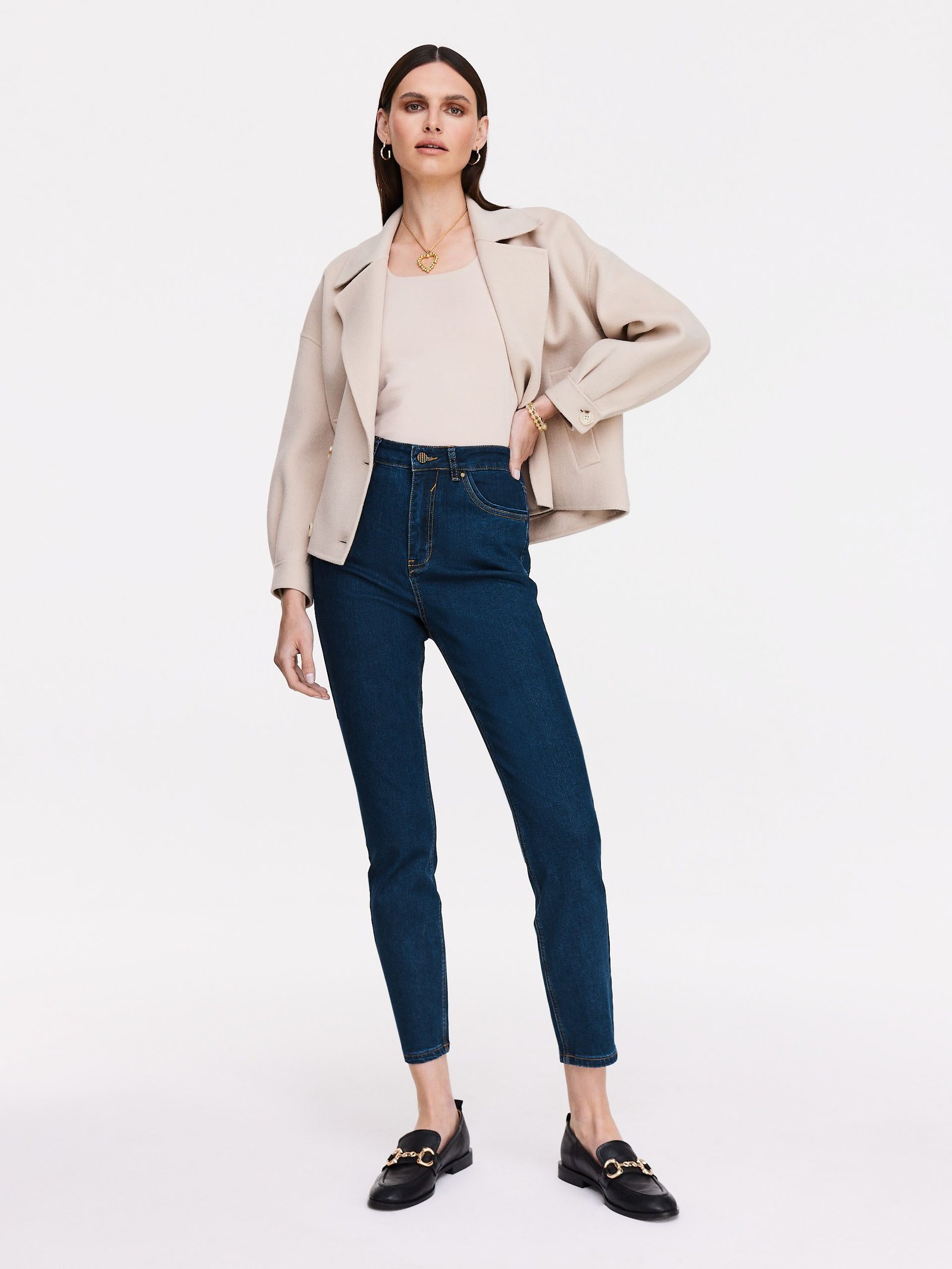 Woman wearing cream blazer with floral blouse and jeans