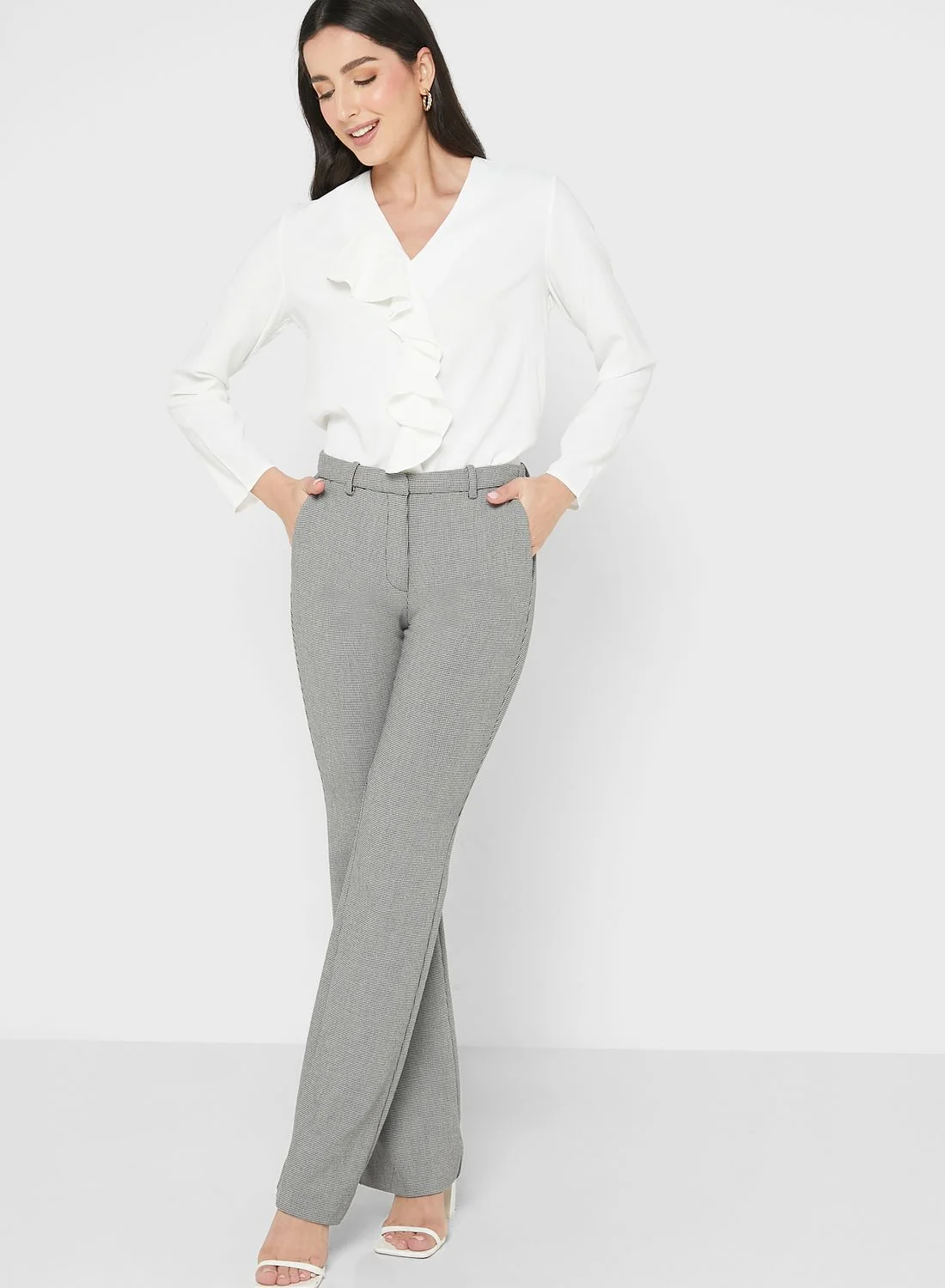 Woman wearing ruffle blouse with high-waist trousers