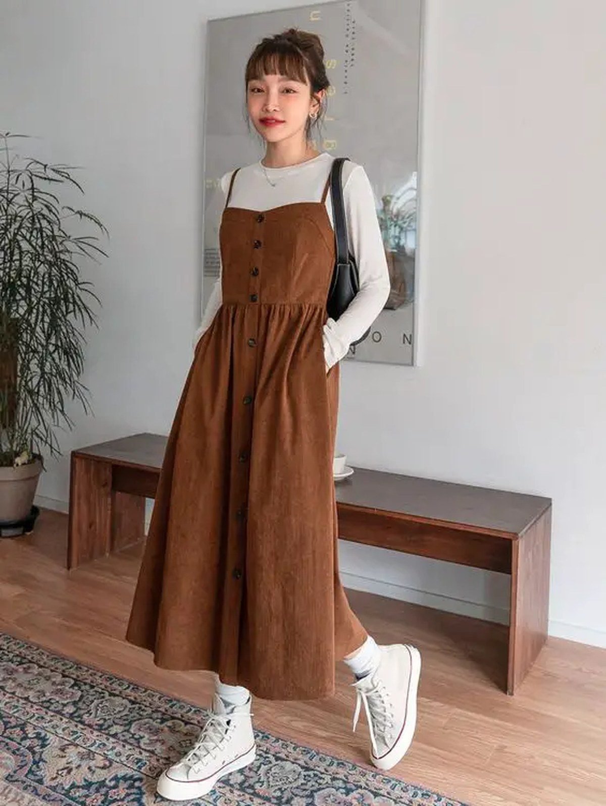 Woman in rust corduroy pants with a cream sweater and neutral sneakers