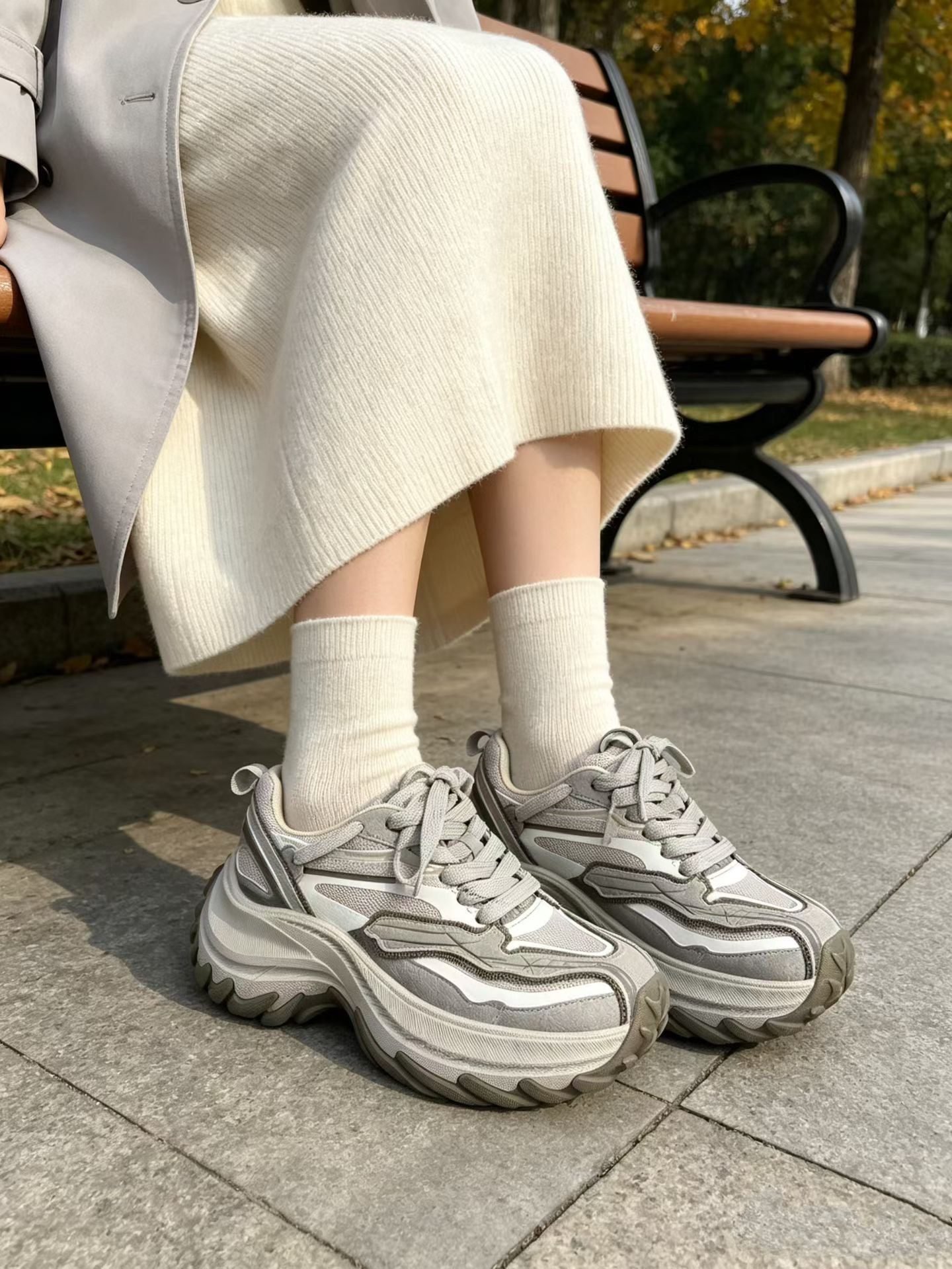 Woman wearing a sweater vest over a white shirt with a pleated skirt and sneakers