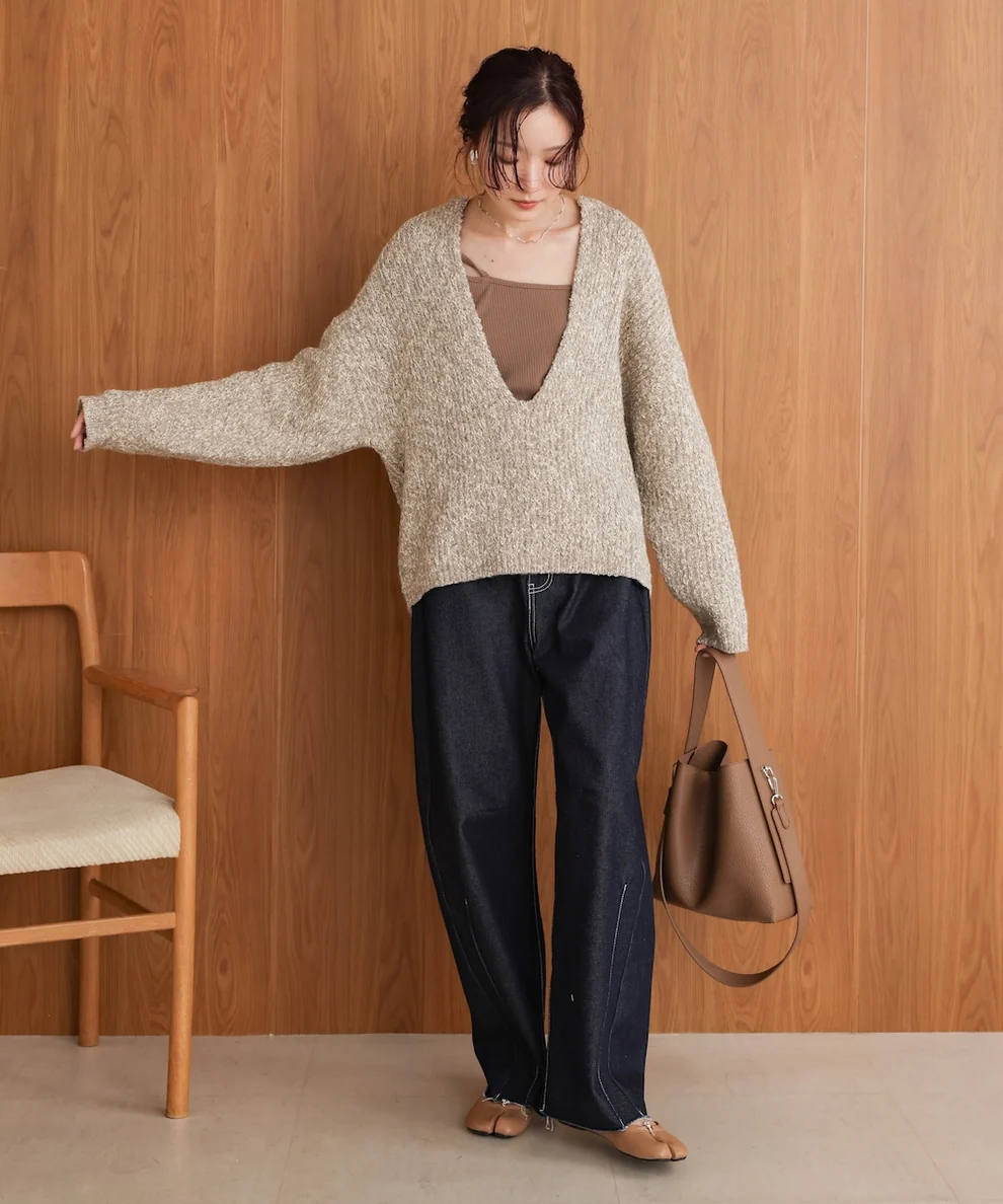 Woman in oatmeal sweater and dark jeans