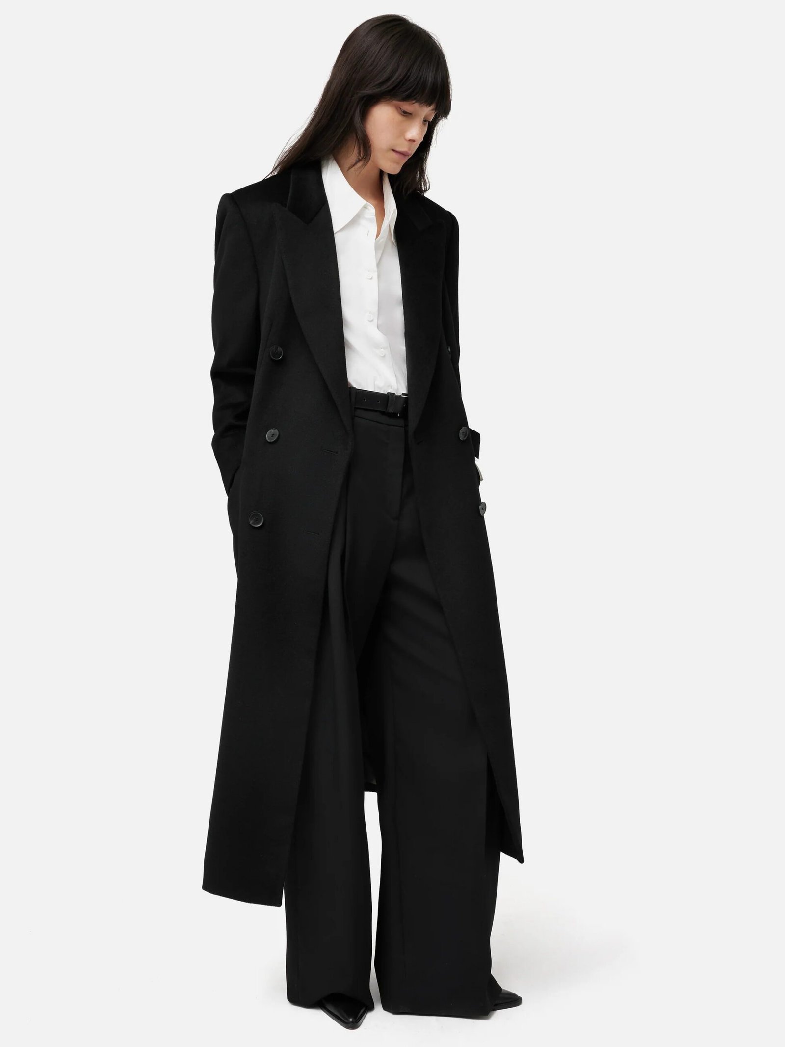 Woman in long black coat with white tee and black trousers