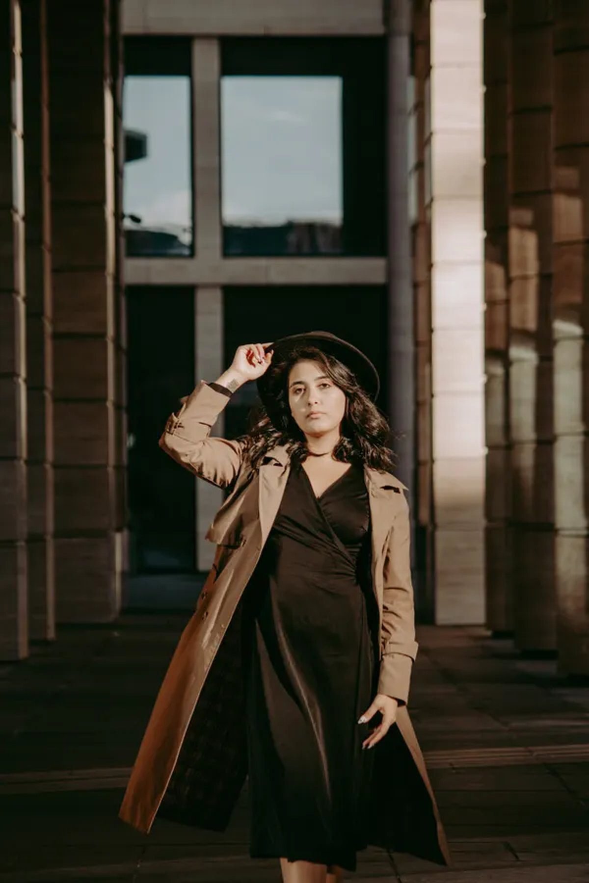 Woman in a black evening gown styled with a classic beige trench coat