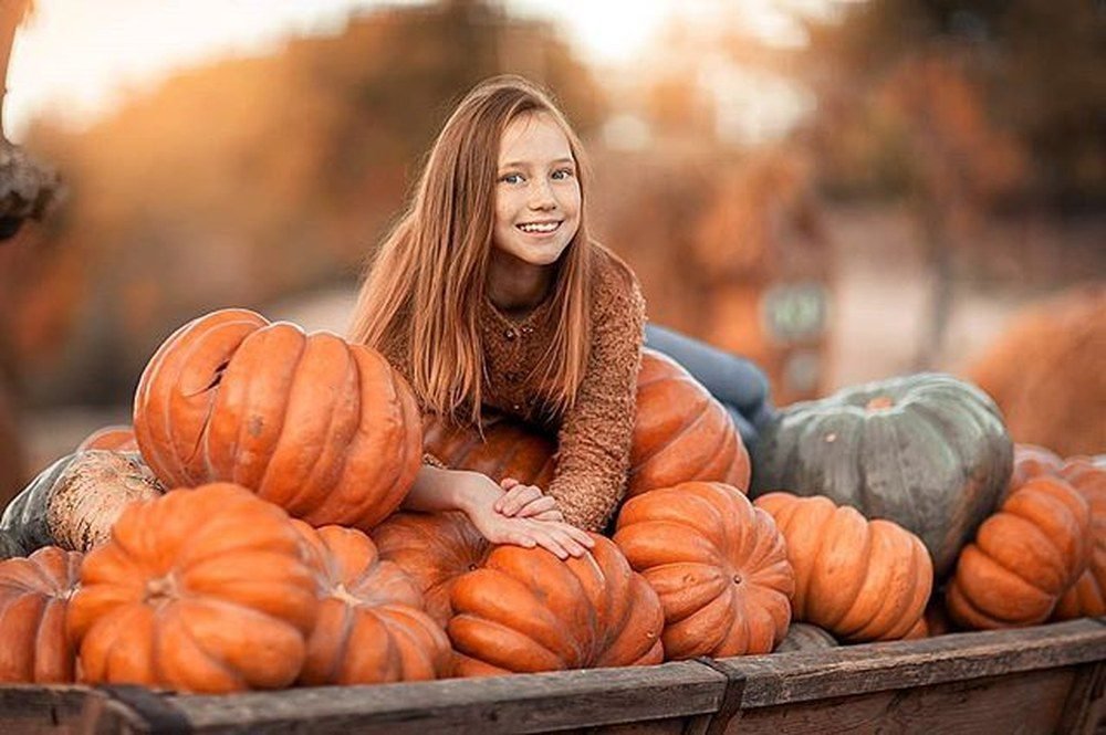 Woman sitting in wheelbarrow wearing corduroy overalls