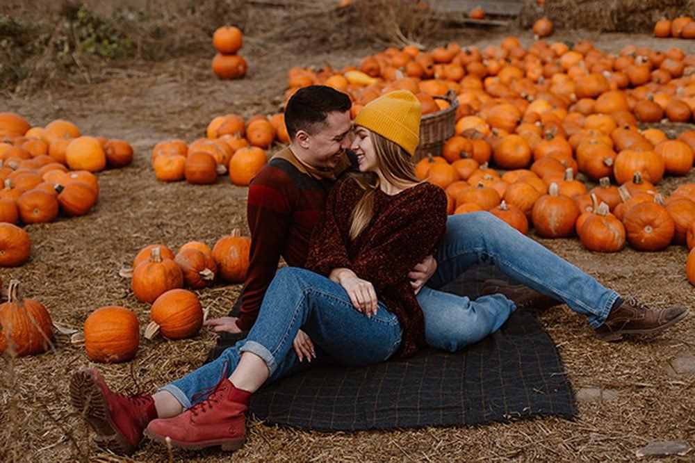 Woman climbing pumpkin display wearing utility jacket and leggings