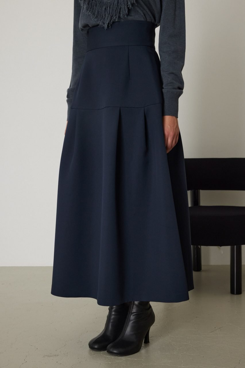 Woman in navy pleated midi skirt with gray sweater