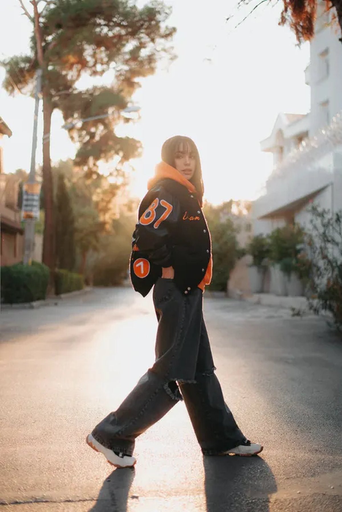 Woman in a vintage varsity jacket with jeans and sneakers