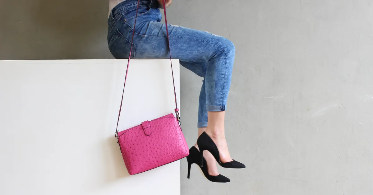 Woman in jeans and t-shirt carrying an evening clutch bag