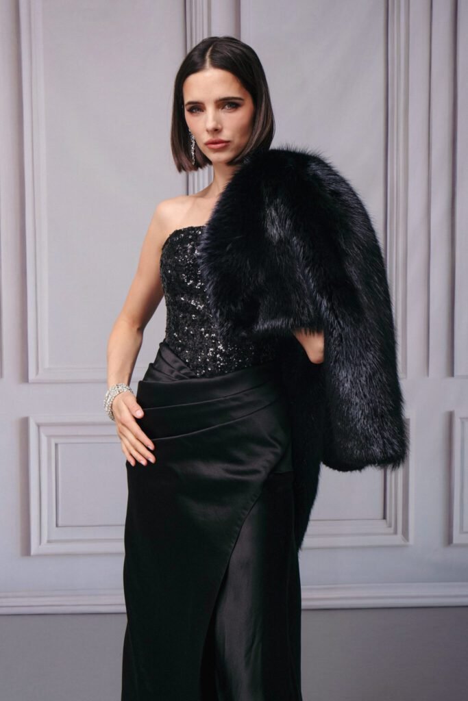 Woman wearing faux fur vest over all-black outfit for evening
