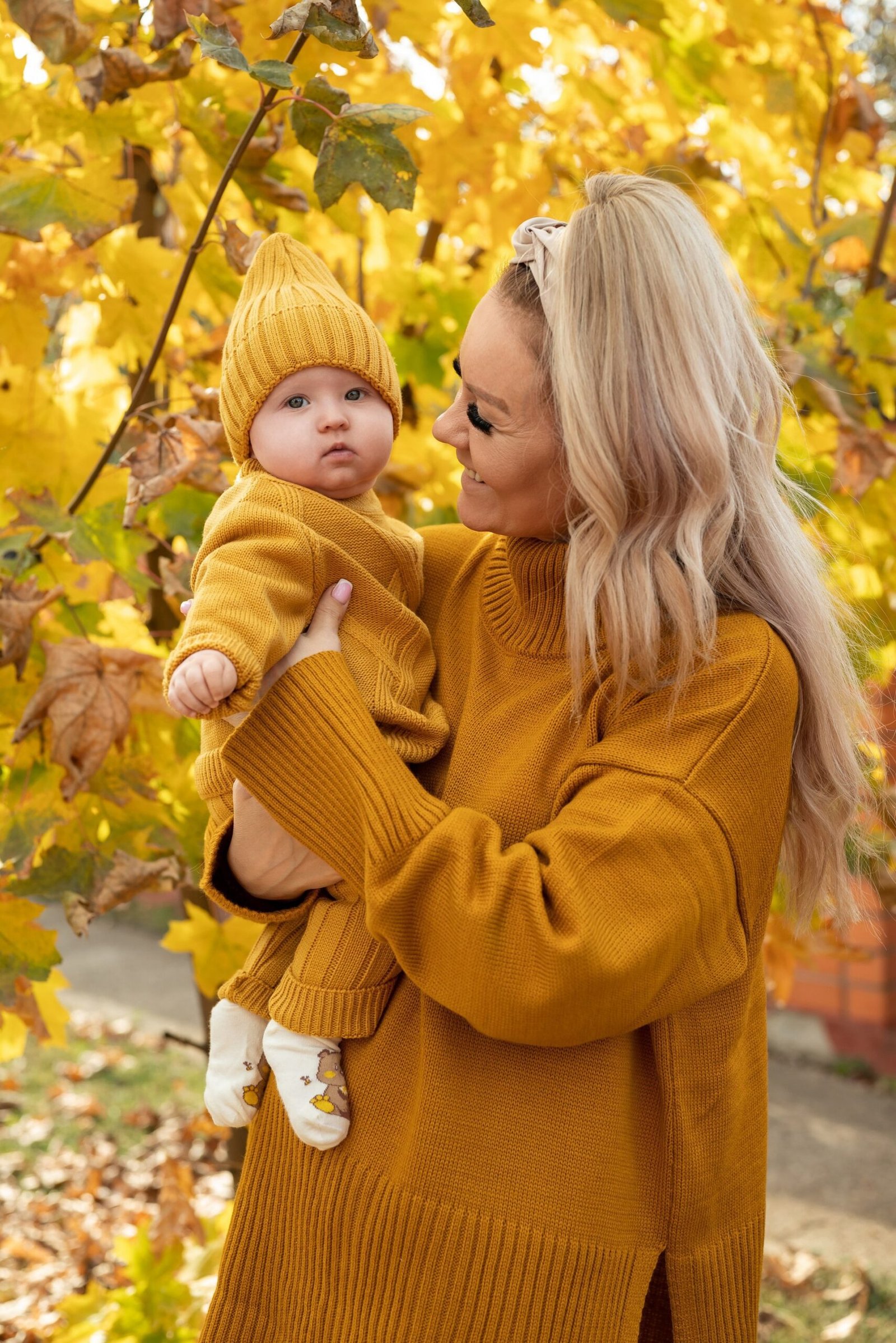 Mom and toddler in red dresses with cardigans at pumpkin patch