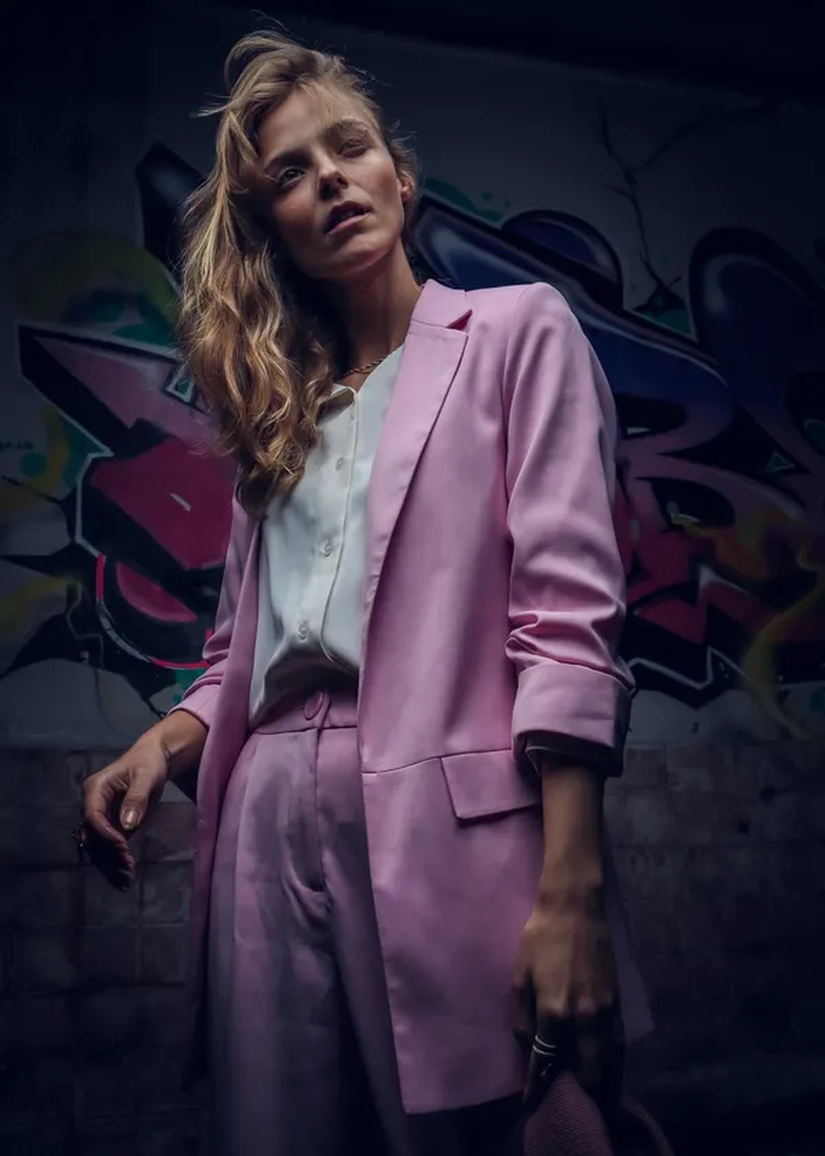 Woman in a pastel pink power-shoulder blazer with white trousers