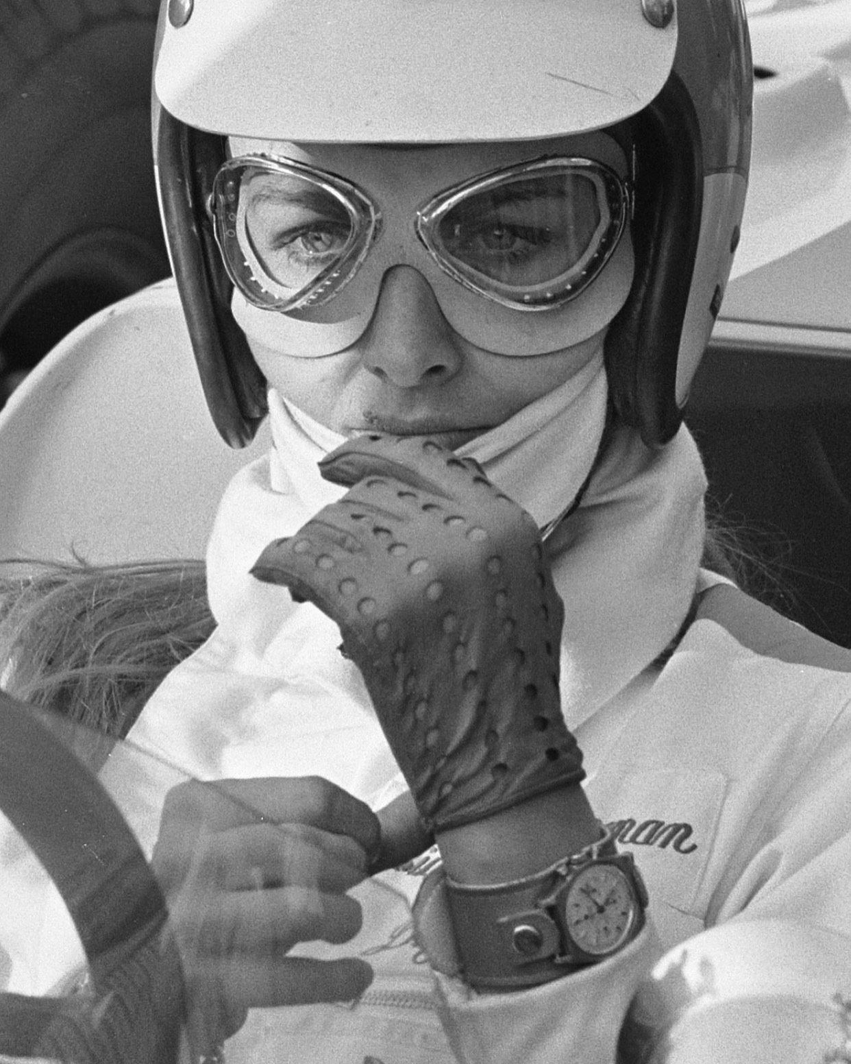 Woman in vintage 1960s racecar driver costume with leather jacket and scarf