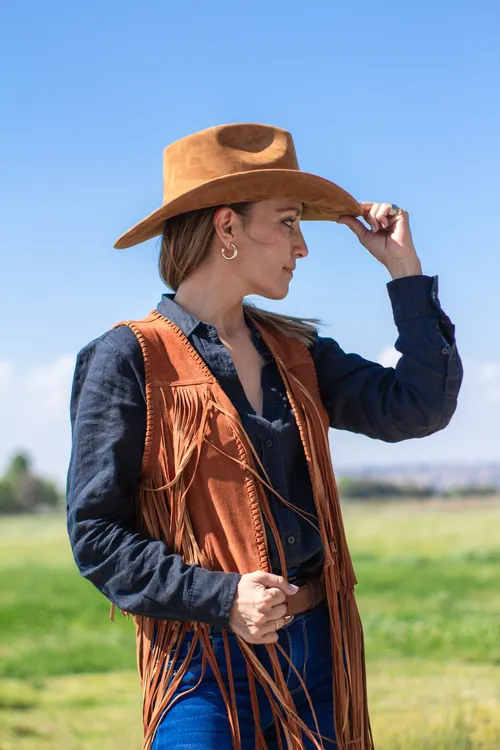Woman wearing a cowgirl baddie Halloween costume with hat and boots