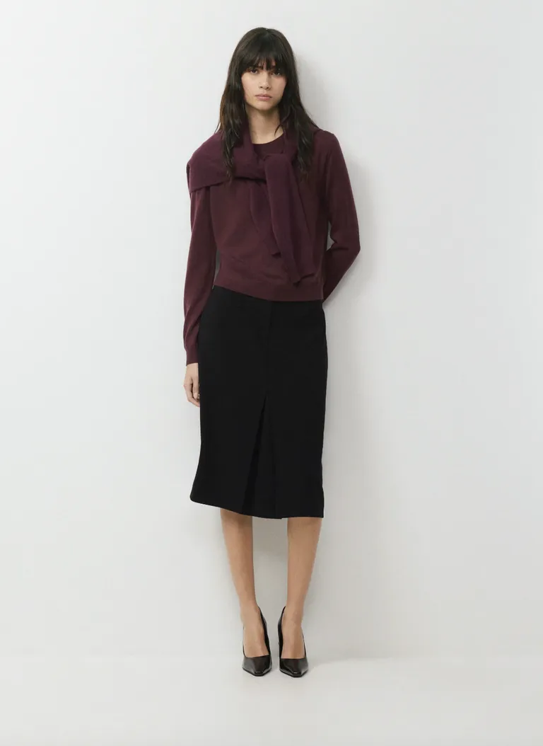 Woman wearing a burgundy sweater with a black midi skirt