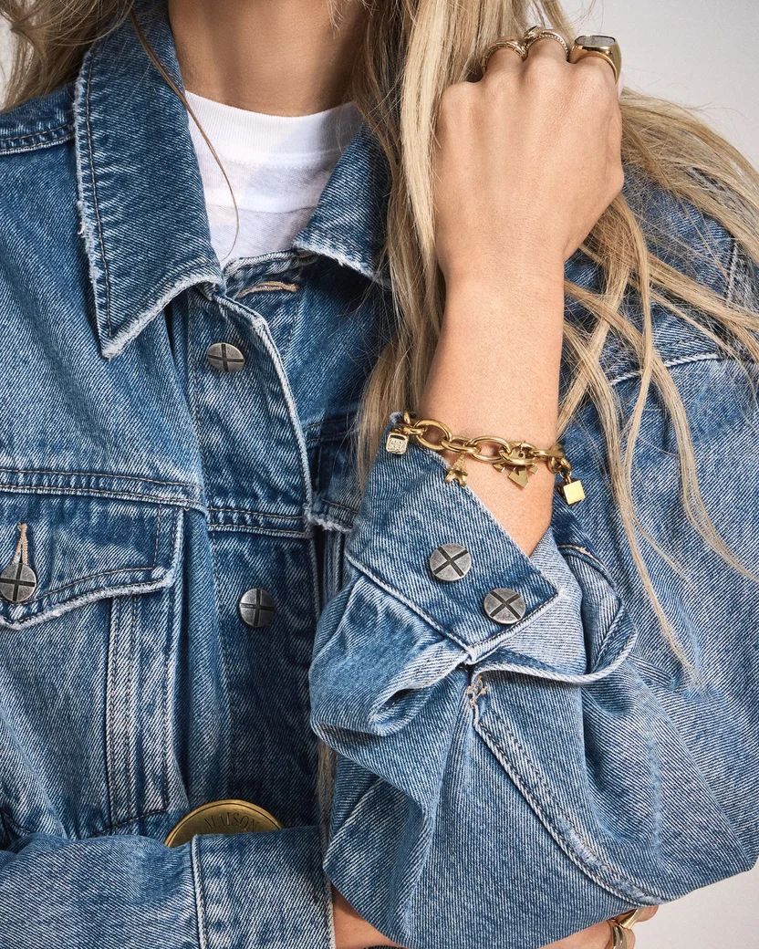 Woman wearing a denim jacket and jeans with a celestial charm bracelet