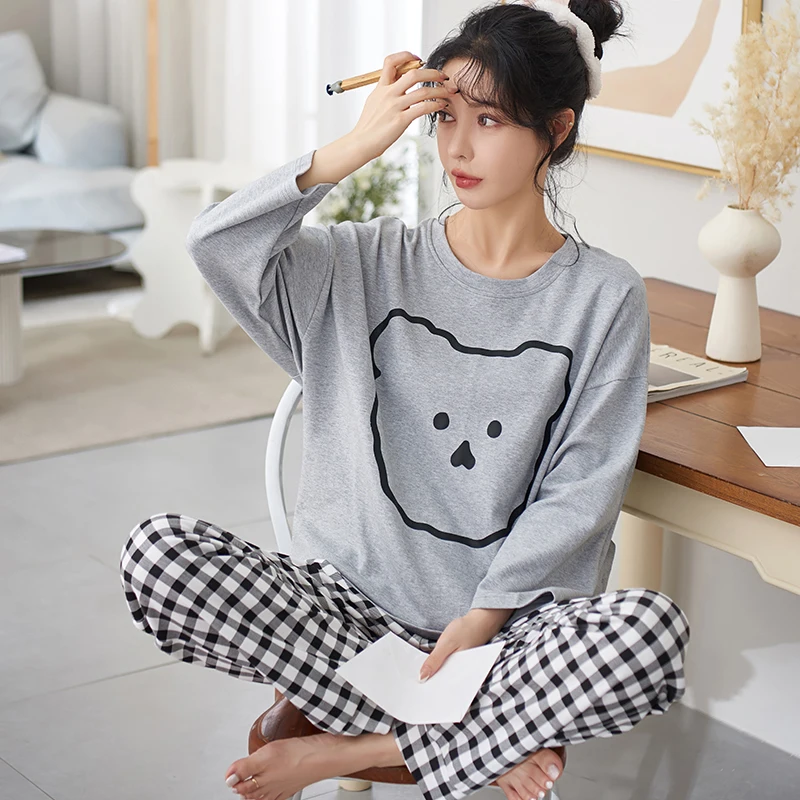 Woman wearing sweatshirt with plaid pajama pants at home