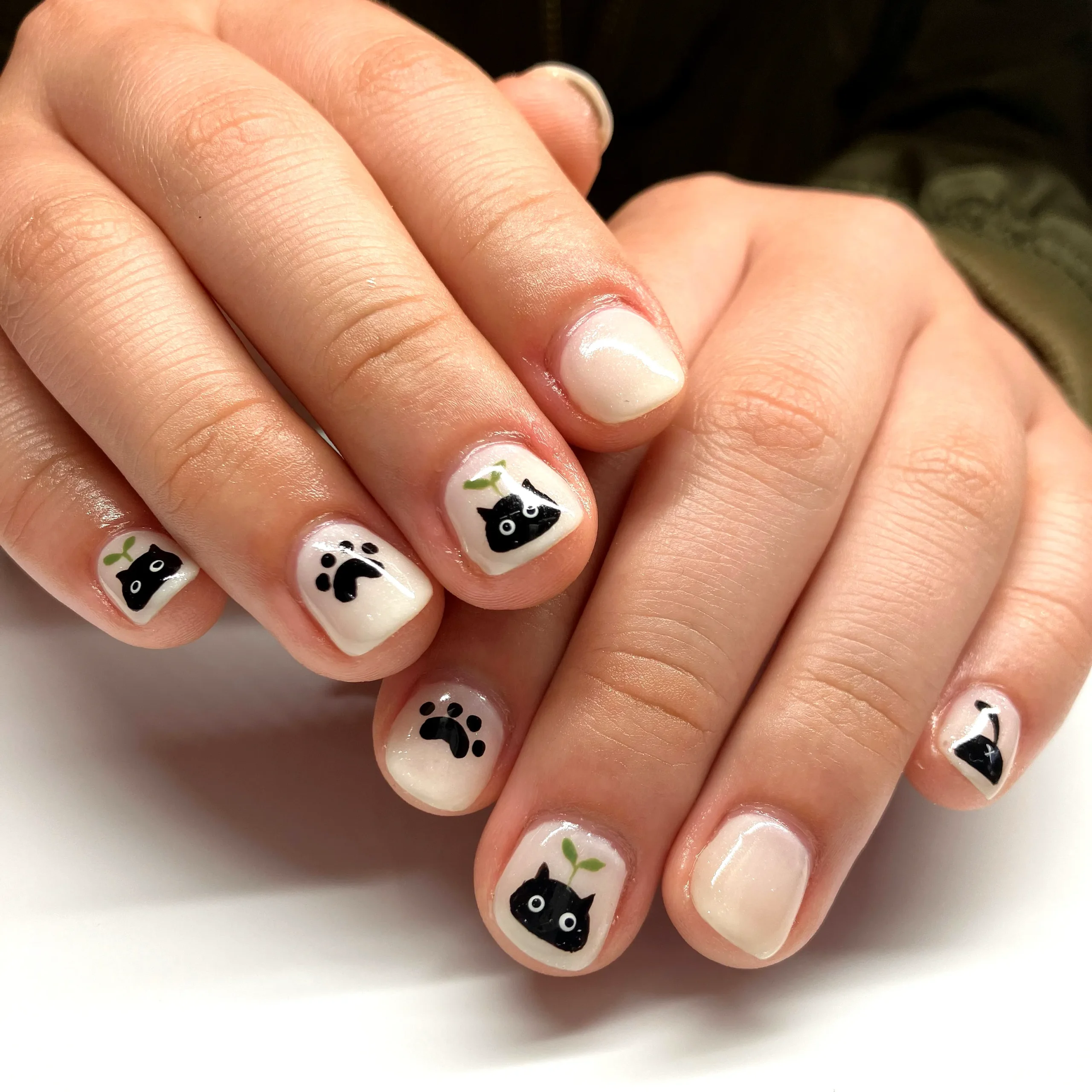 Black cat eyes peeking from dark Halloween nails