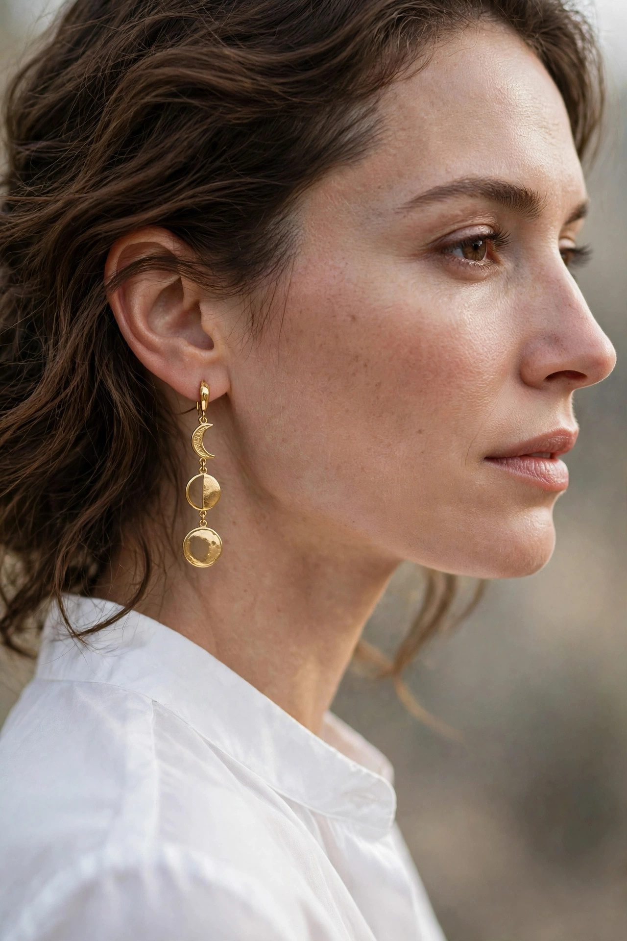 Woman wearing a white blouse with moon phase earrings