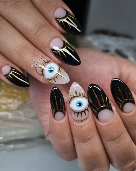 Black nails with small gold evil eye nail art