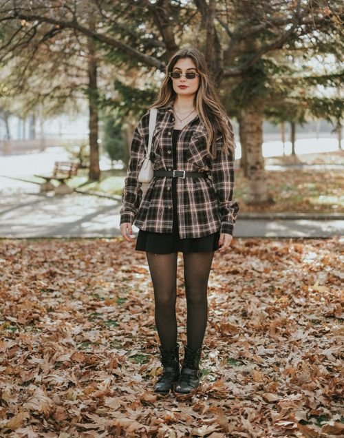 Woman wearing a flannel shirt dress with tights and boots