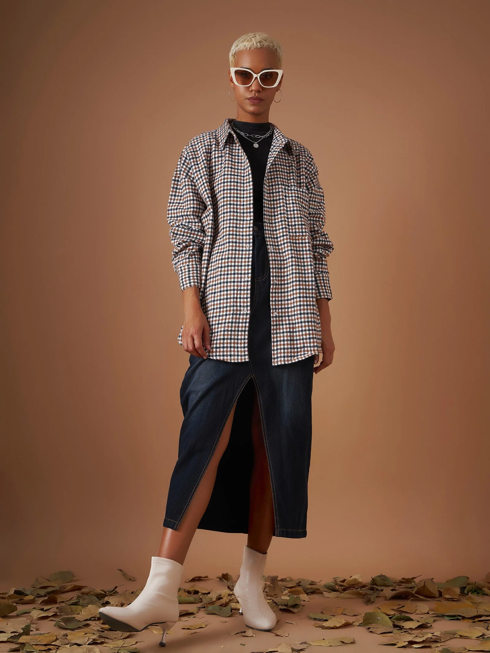 Woman wearing a flannel shirt with a midi skirt and boots
