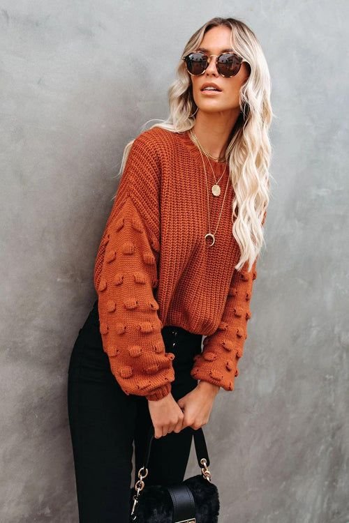 Woman wearing a rust-colored sweater with black jeans