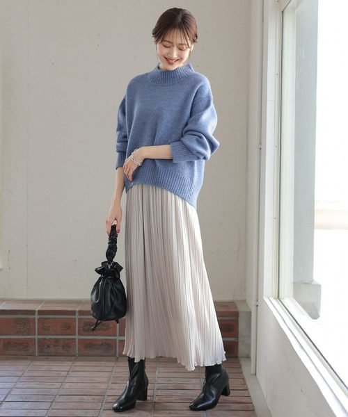 Woman wearing a mock-neck sweater with a pleated skirt