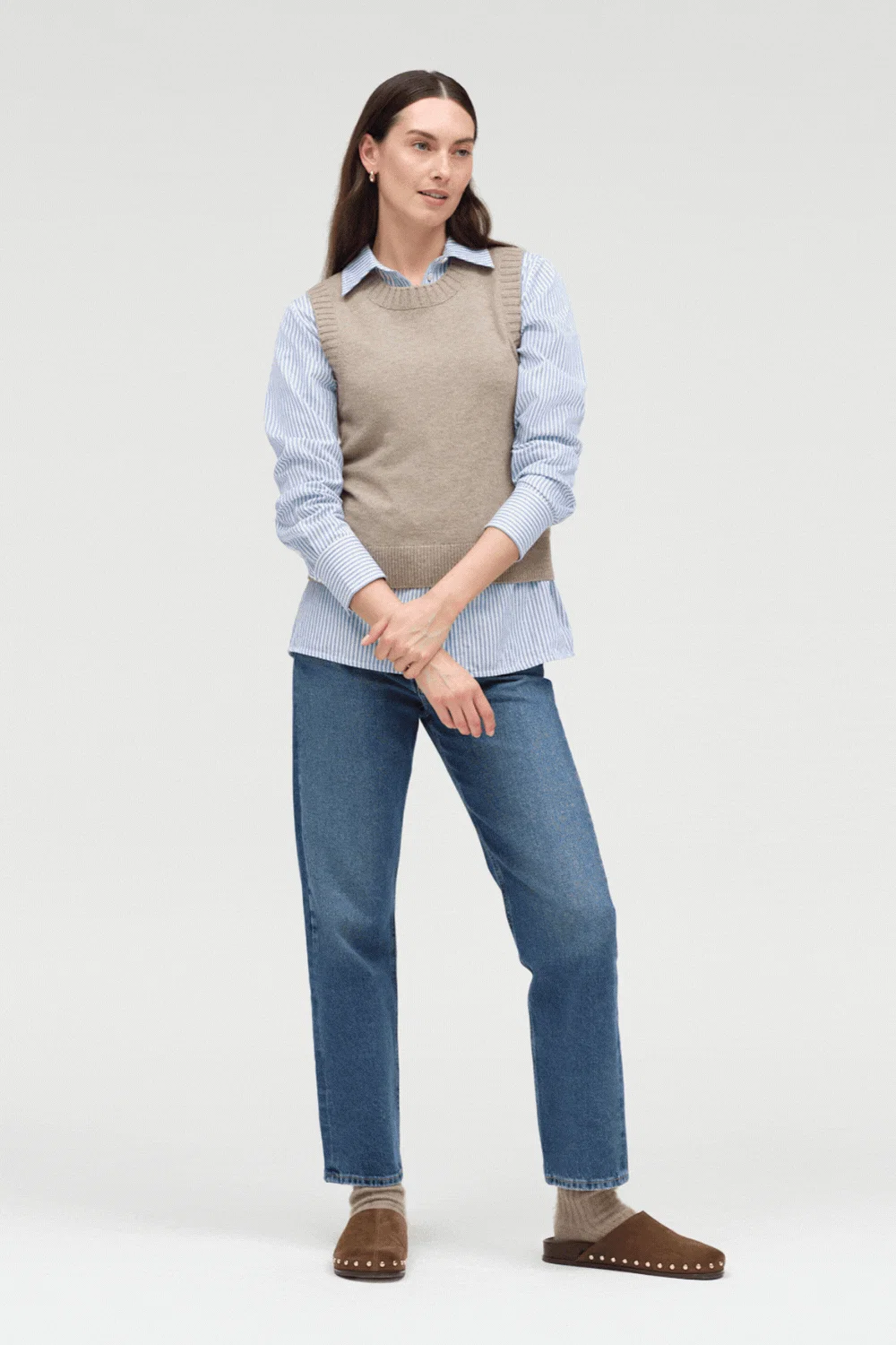 Woman wearing a sweater vest over a button-down shirt with jeans