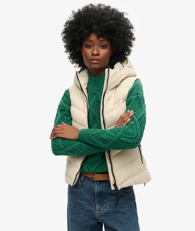 Woman wearing a hooded sweater with a puffer vest and jeans