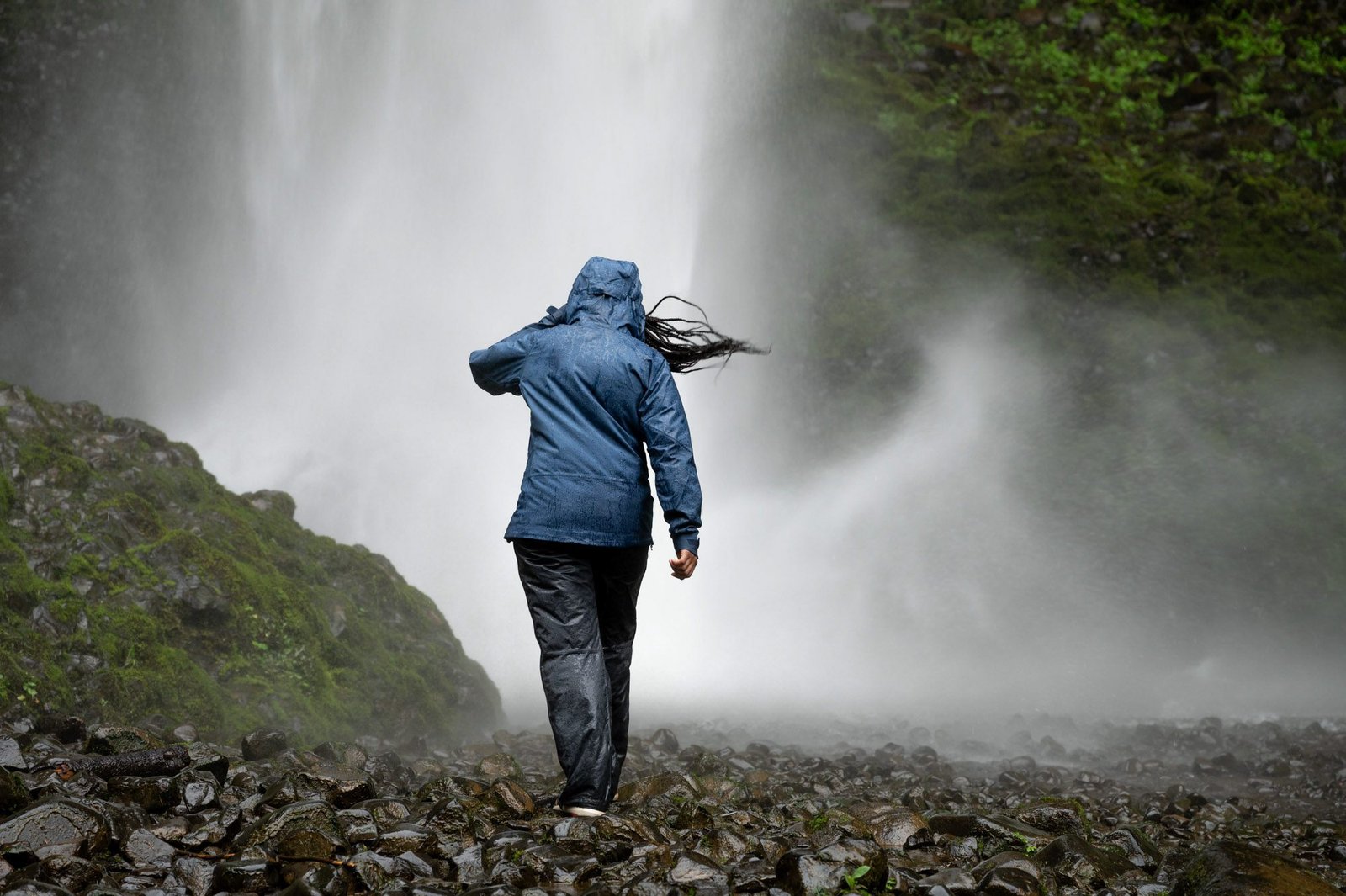 Woman in anorak jeans and hiking boots with backpack rainy trail